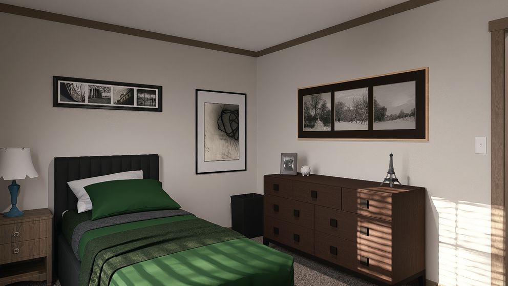 A tidy bedroom with a green bedspread, dresser, mirror, and framed wall art in warm light.