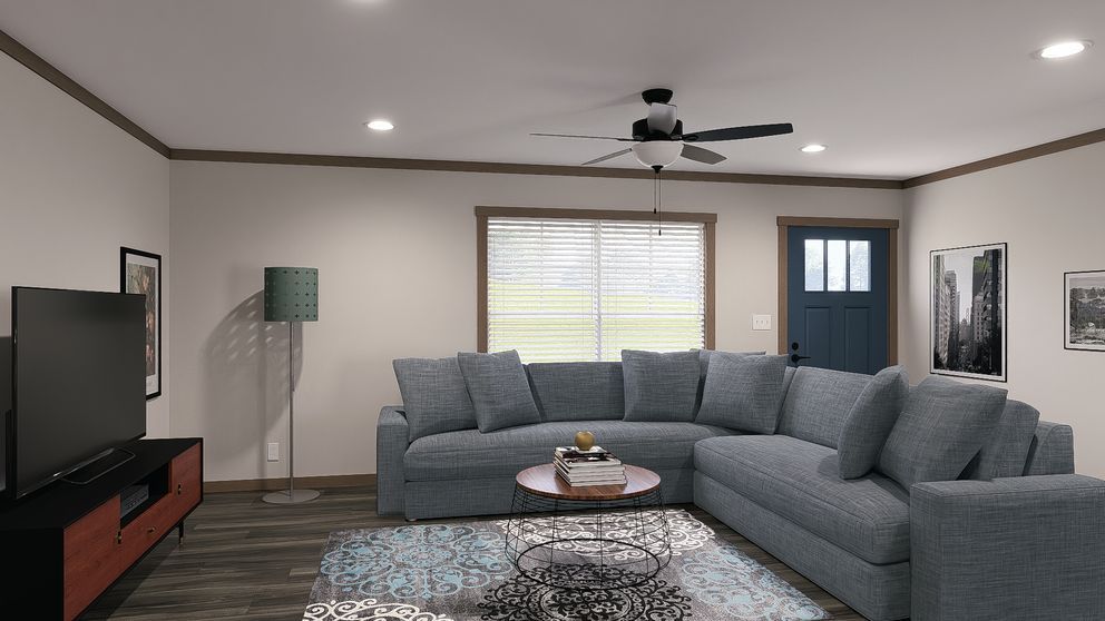 Modern living room with a gray sectional sofa, TV, coffee table, and ceiling fan near a front door.