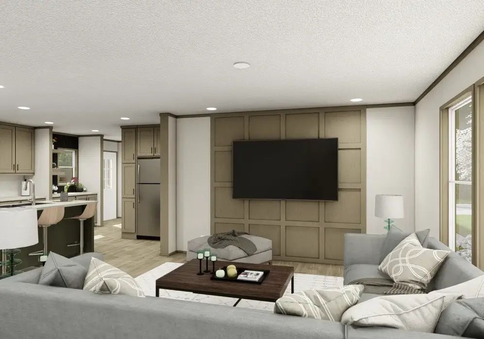 Modern living room with gray sectional sofa, wall-mounted TV, coffee table, and open kitchen area.