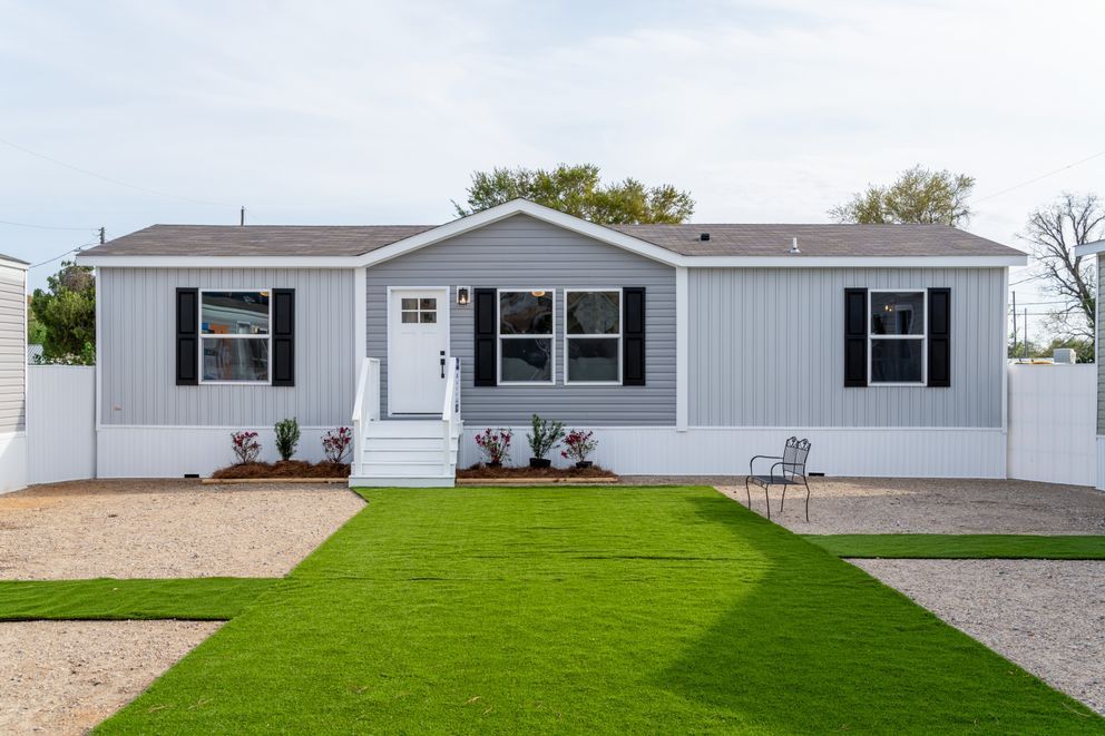 White single-story house with gray roof, black shutters, and a bright green front lawn.