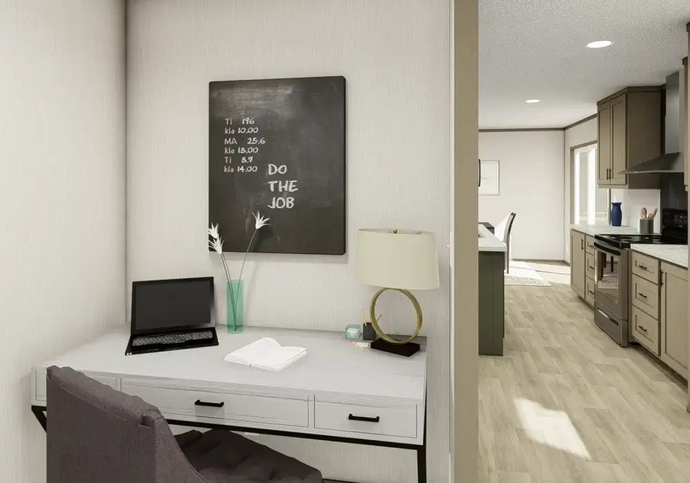 Modern home office with gray desk, laptop, chalkboard art, and view into a kitchen area