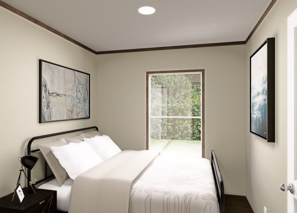 Small bedroom with a bed, wall art, and a bright windowed door opening to greenery