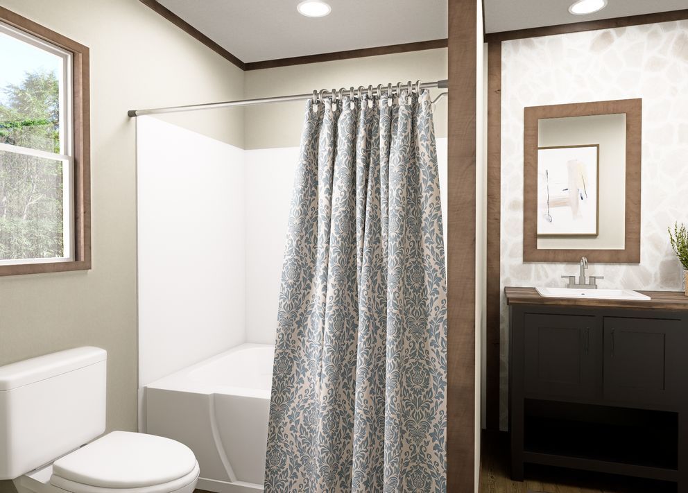 Small bathroom with a shower curtain, toilet, sink, and mirror in neutral tones.