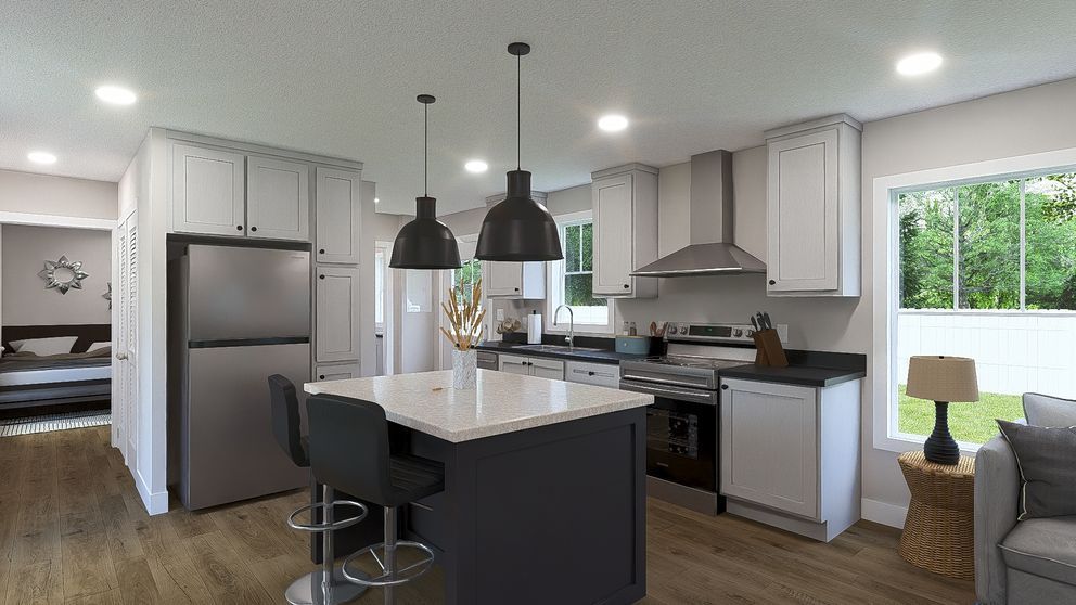 Modern open kitchen with gray cabinets, island stools, stainless fridge, and bright windows overlooking greenery