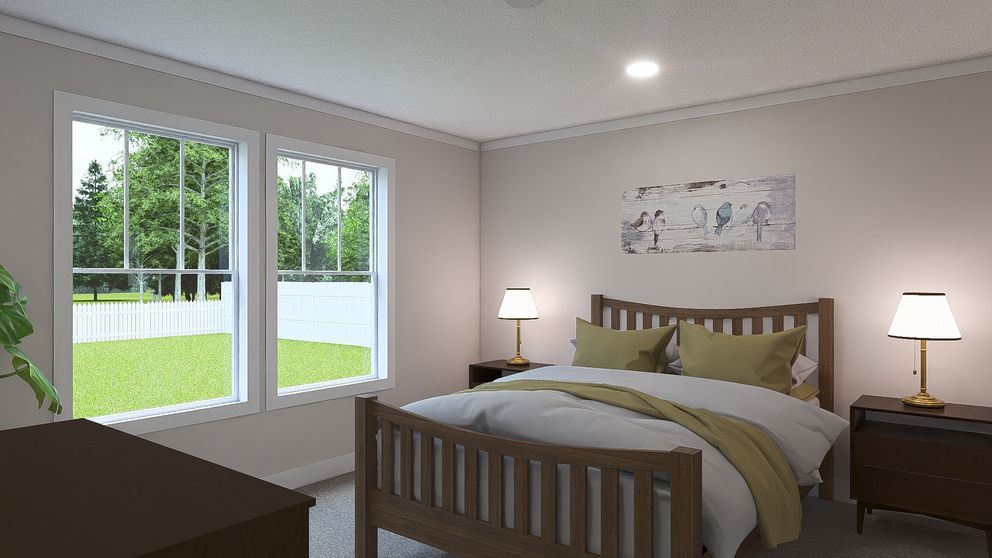 Neat bedroom with wooden bed, bedside lamps, dresser, and sliding glass doors to a green yard.