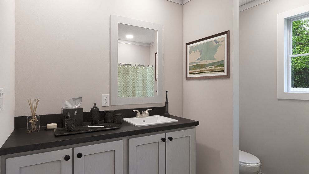 Bathroom vanity with mirror, black countertop, sink, framed wall art, and a window.
