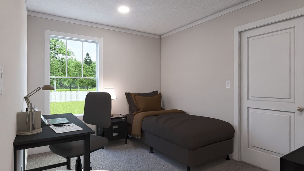 Small bedroom with a twin bed, desk, chair, and window letting in daylight.