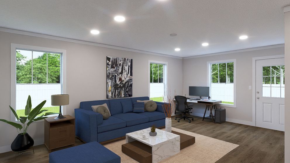 Bright living room with blue sofa, desk, coffee table, plants, and large windows.