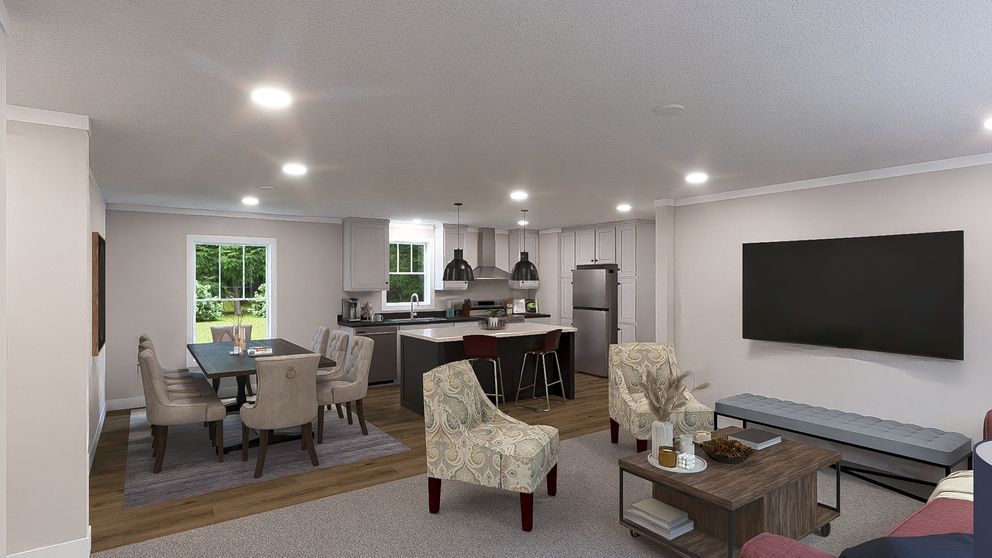 Modern open-plan living room with gray sectional, dining area, kitchen, and large wall-mounted TV