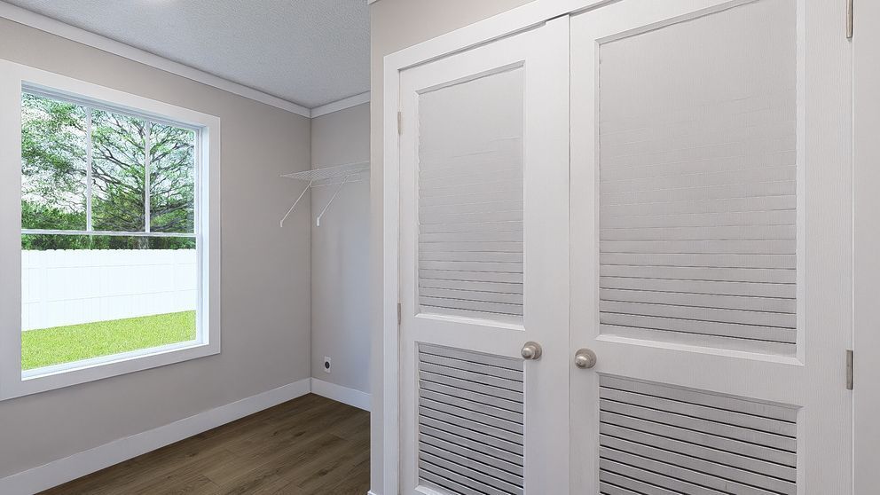 Bright bedroom with white closet doors, window, and wood flooring.