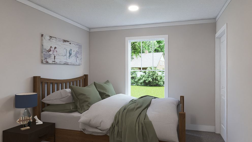 Cozy bedroom with a neatly made bed, nightstand lamp, and window view of green trees