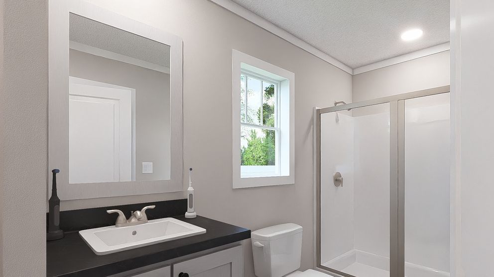 Modern bathroom with vanity, mirror, toilet, and glass shower under a window