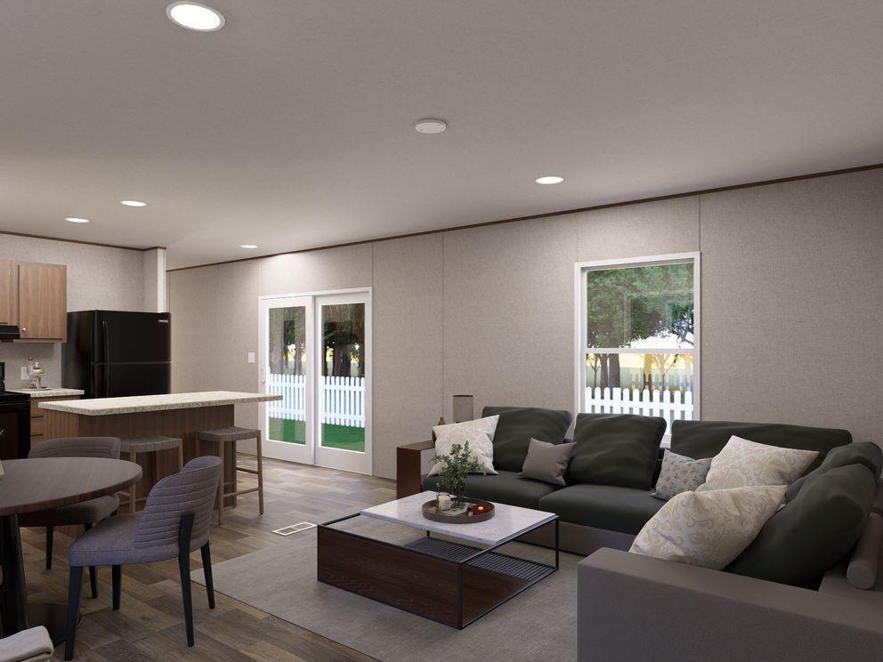 Modern open-plan living room with gray sectional, coffee table, dining area, and kitchen in the background
