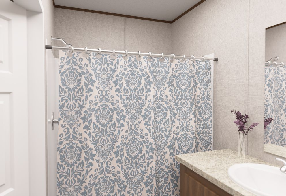 Bathroom with blue patterned shower curtain, granite countertop, sink, mirror, and purple flowers