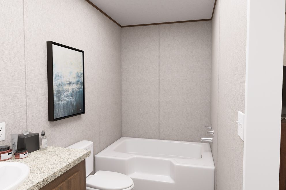 Modern bathroom with a white soaking tub, toilet, vanity, and framed wall art