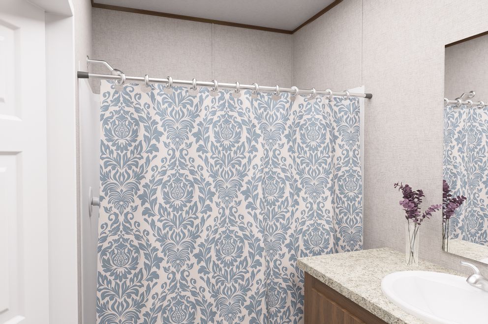Bathroom with light blue patterned shower curtain, white sink, and speckled countertop