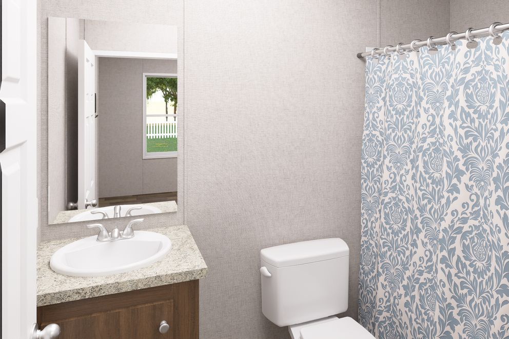 Small bathroom with vanity sink, mirror, toilet, and blue patterned shower curtain.