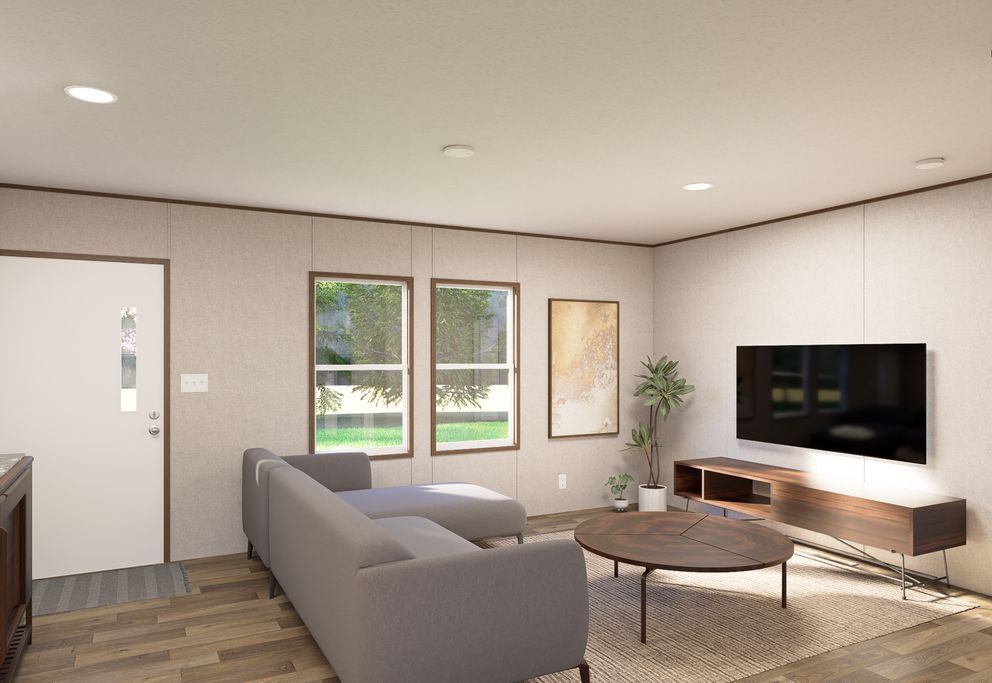 Modern living room with gray sofa, wall-mounted TV, coffee table, and large windows overlooking a yard