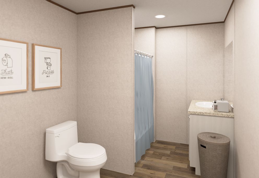 Small beige bathroom with toilet, shower curtain, sink, and trash bin.