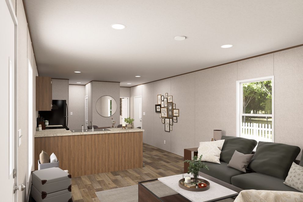 Modern open-concept living room with kitchen, gray sofa, coffee table, and wood flooring.