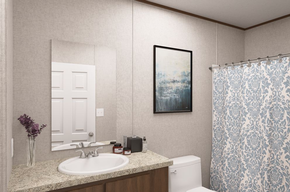 Bathroom with granite vanity, oval sink, mirror, framed art, toilet, and blue patterned shower curtain.