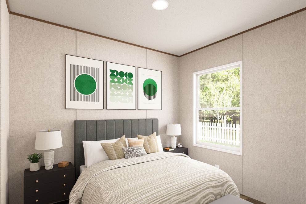 Bright bedroom with a bed, bedside tables, framed art, and sunlight through a window