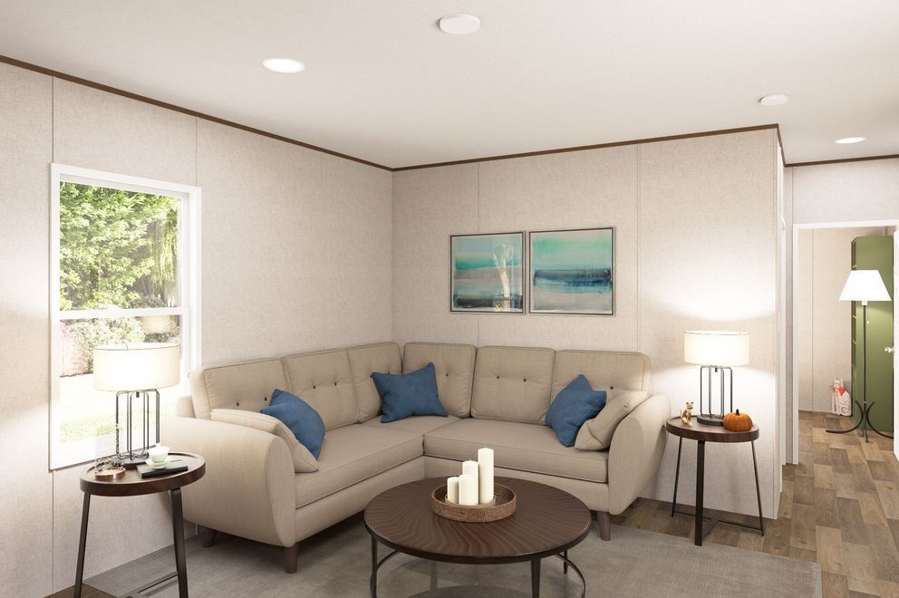 Modern living room with beige sectional sofa, blue pillows, coffee table, and wall art near a window.