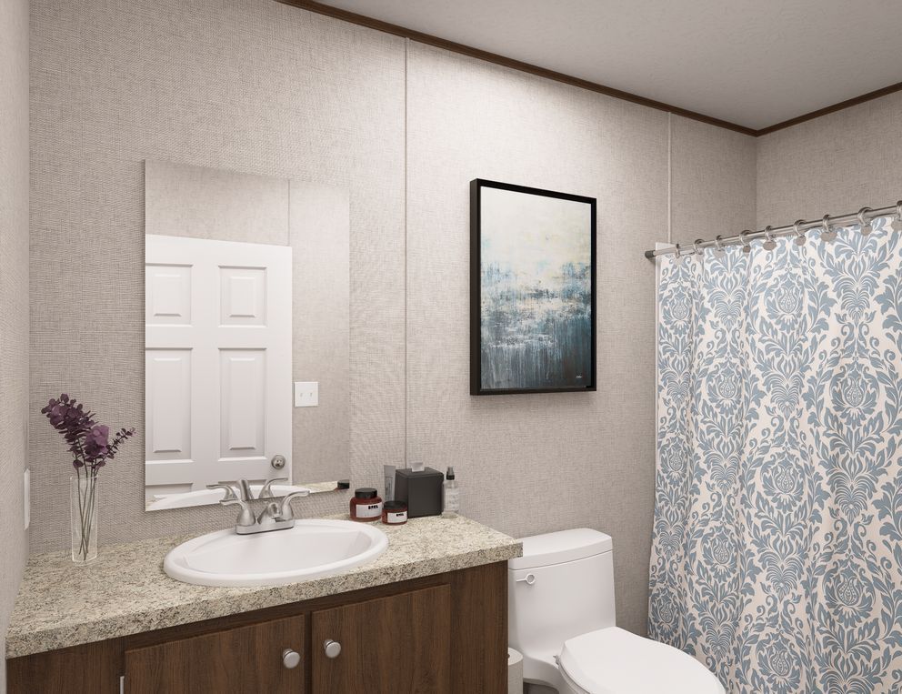 Small bathroom with vanity sink, mirror, toilet, and blue patterned shower curtain.