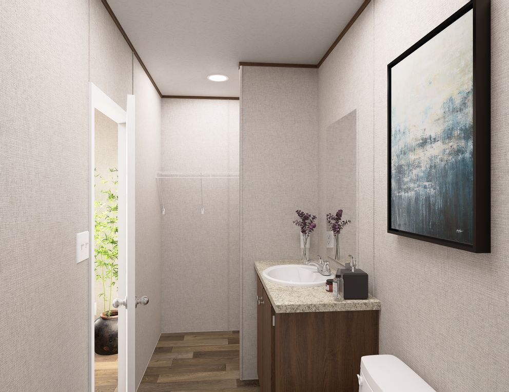 Narrow modern bathroom with white walls, wood vanity, sink, and abstract wall art
