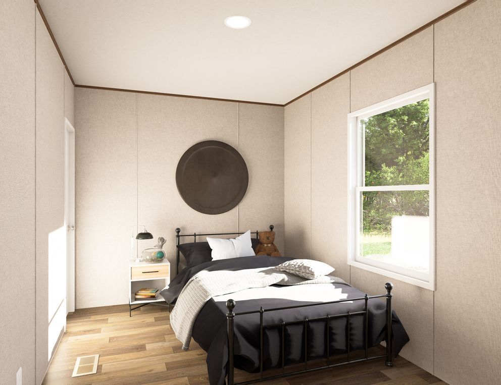 Minimal bedroom with a black bed, beige walls, wood floor, and a window with green trees outside