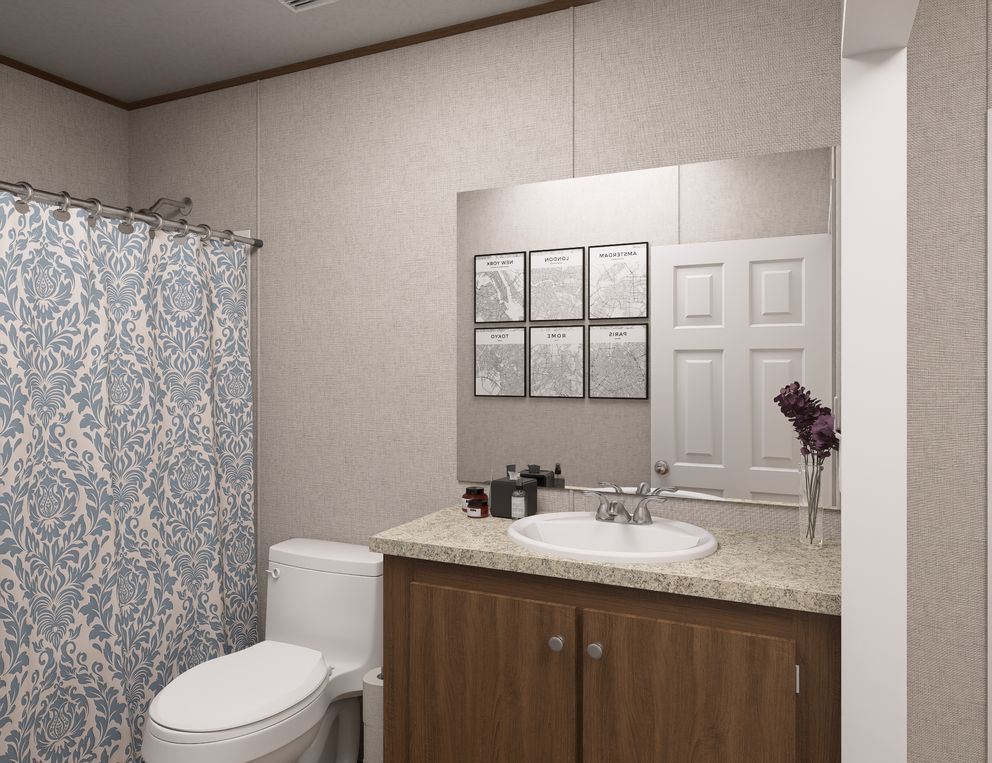 Bathroom vanity with mirror, white sink, toilet, and blue patterned shower curtain