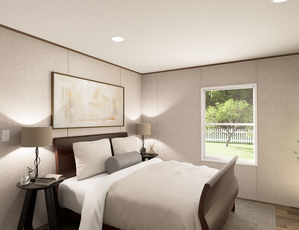 Bright bedroom with a neatly made bed, bedside lamps, and a window overlooking greenery.