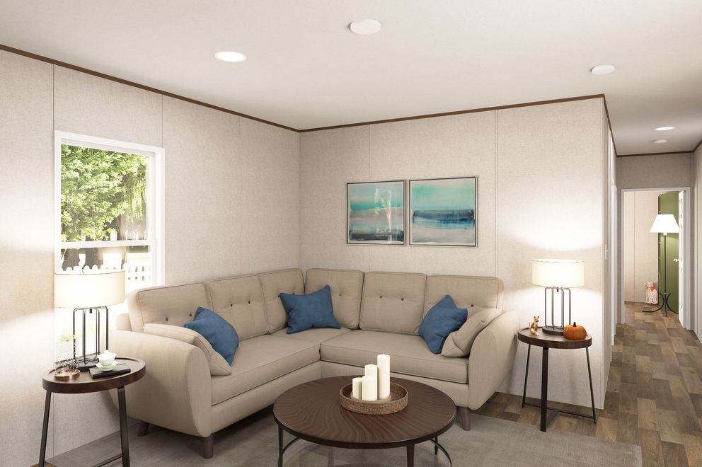 Bright living room with beige sectional, blue pillows, round coffee table, lamps, and wall art.