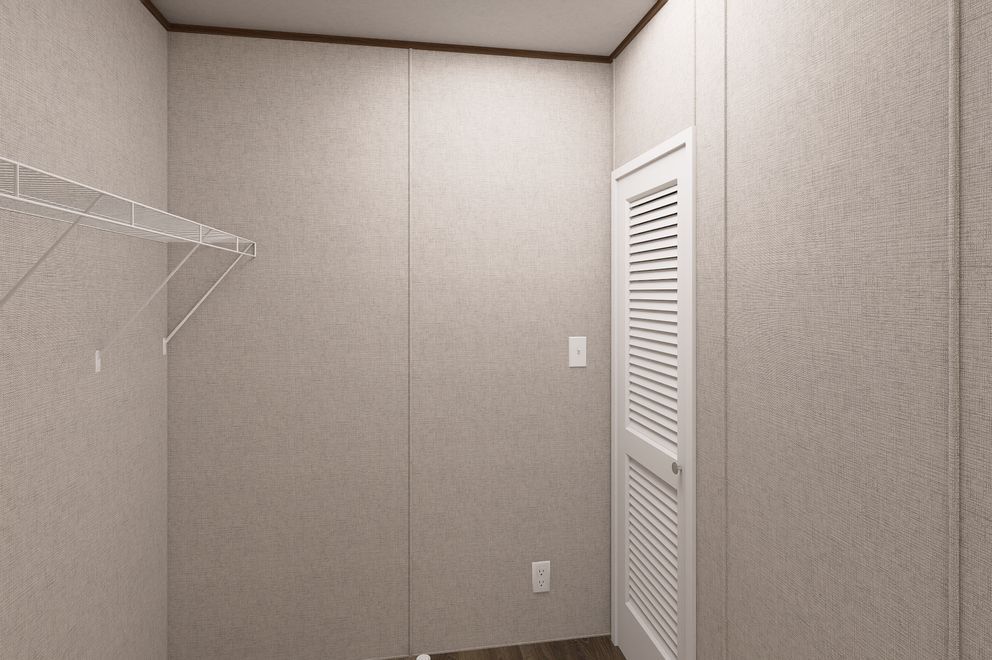 Empty beige closet with wire shelf and white louvered door.