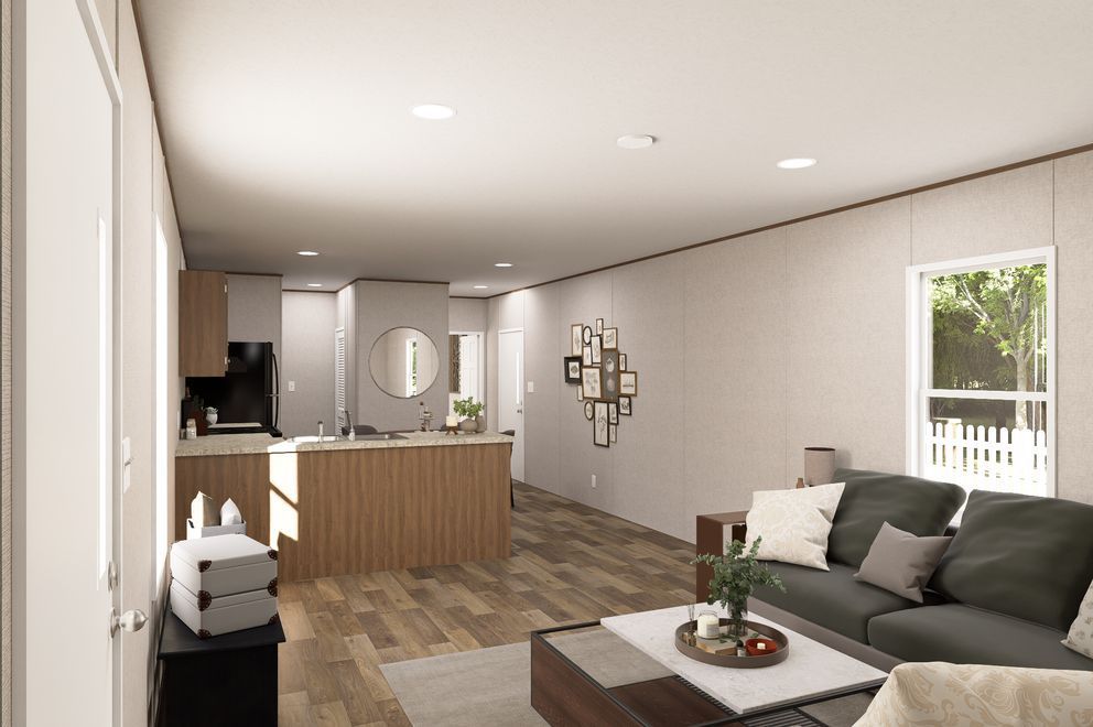 Modern open-plan living room and kitchen with gray sofa, wood flooring, and a bright window.