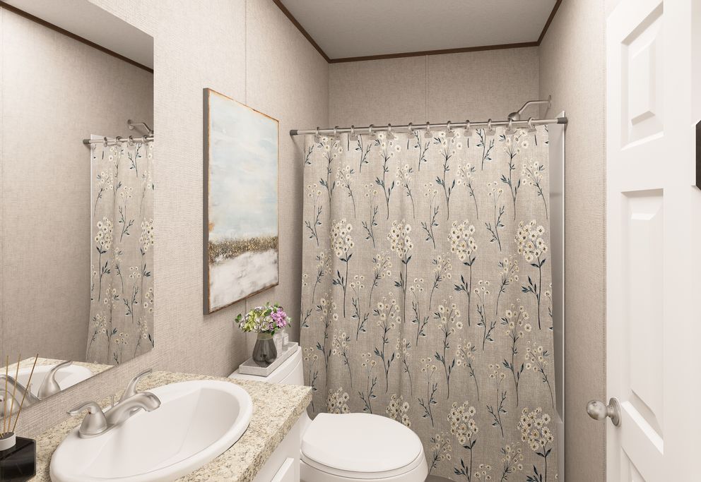 Small beige bathroom with vanity, sink, toilet, shower curtain, and mirror.