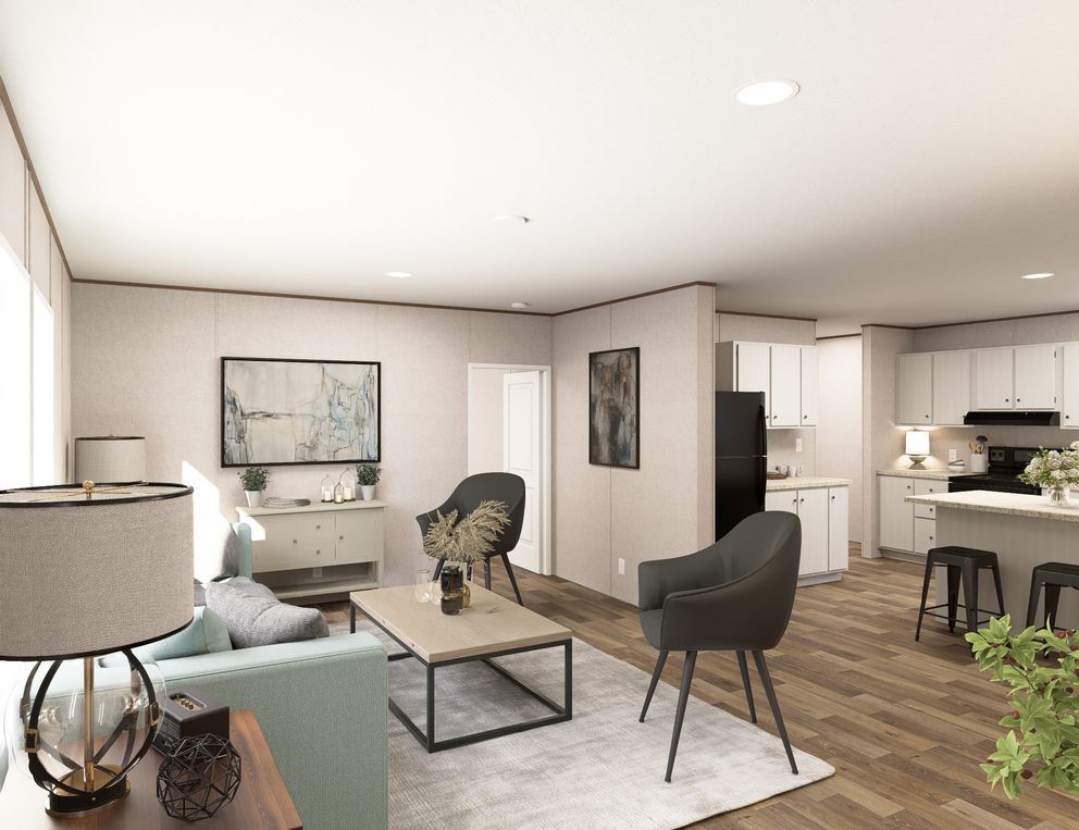 Modern open-concept living room and kitchen with gray chairs, coffee table, and wood floors.