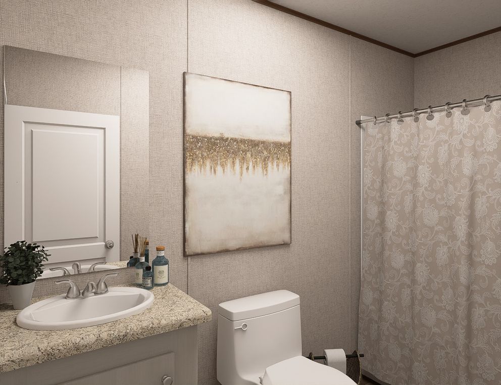 Small beige bathroom with sink, toilet, mirror, shower curtain, and wall art