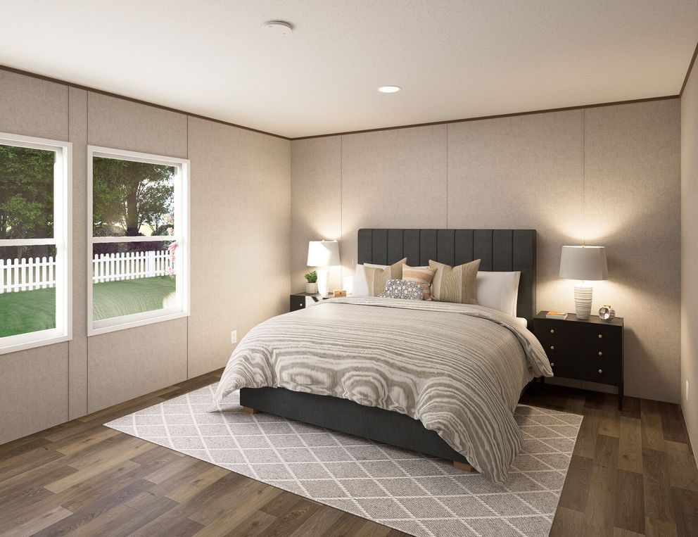 Bright bedroom with a bed, nightstands, lamps, rug, and windows on the left.