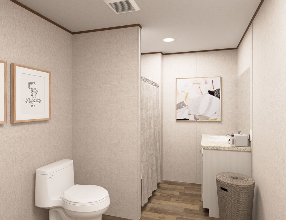 Small beige restroom with toilet, stall, sink, and trash can in a modern office-like setting.