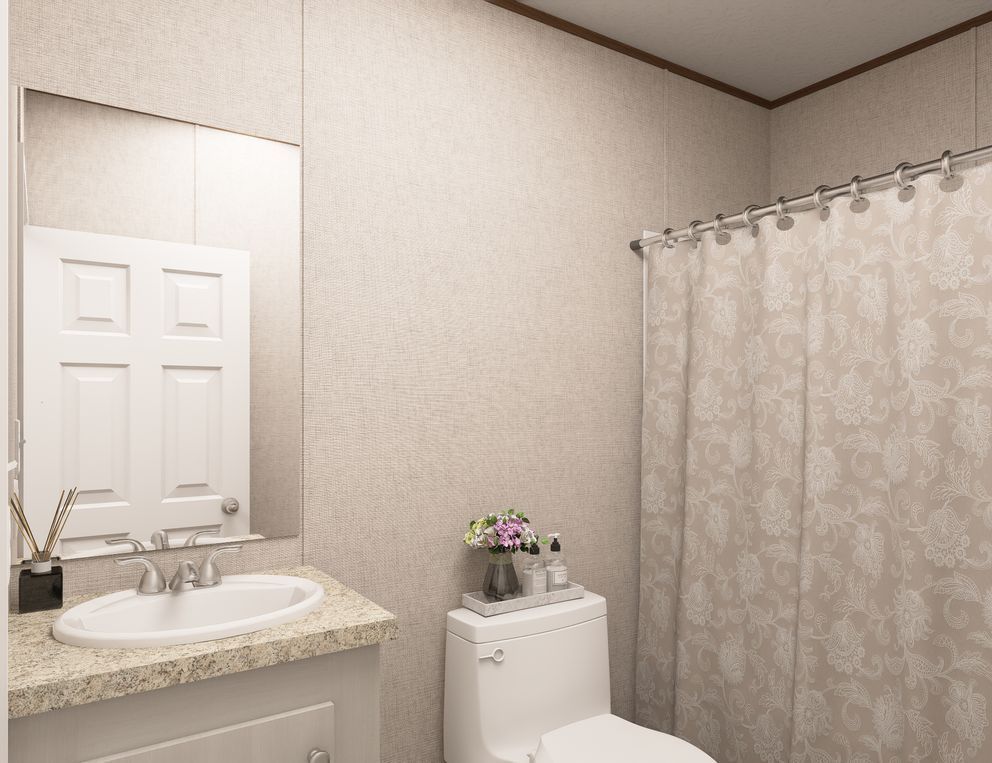 Small bathroom with a sink, mirror, toilet, and shower curtain in beige tones.
