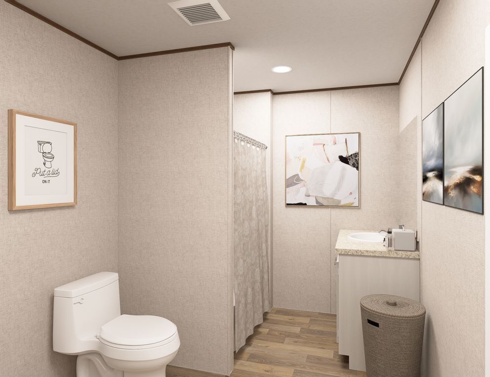 Modern beige bathroom with toilet, shower, vanity, and framed wall art.