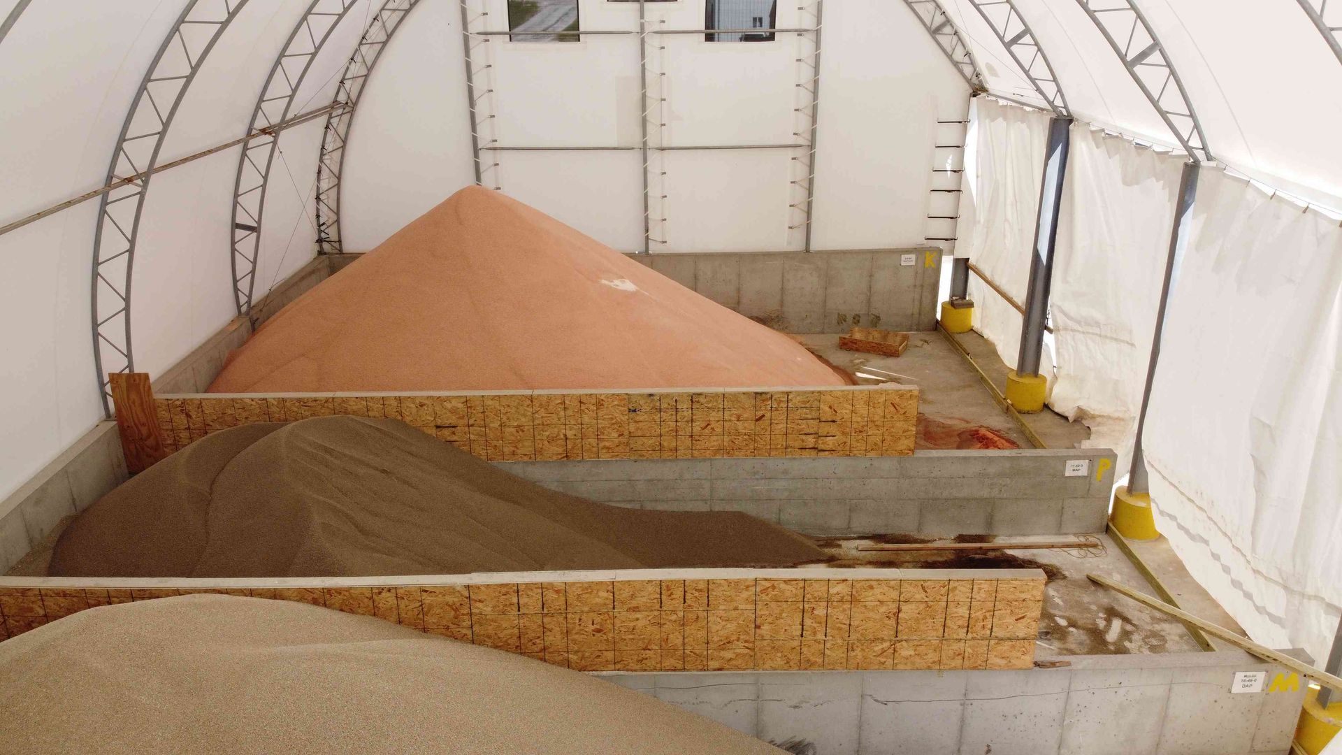 Three piles of material in a covered storage bin: tan, brown, and pink.
