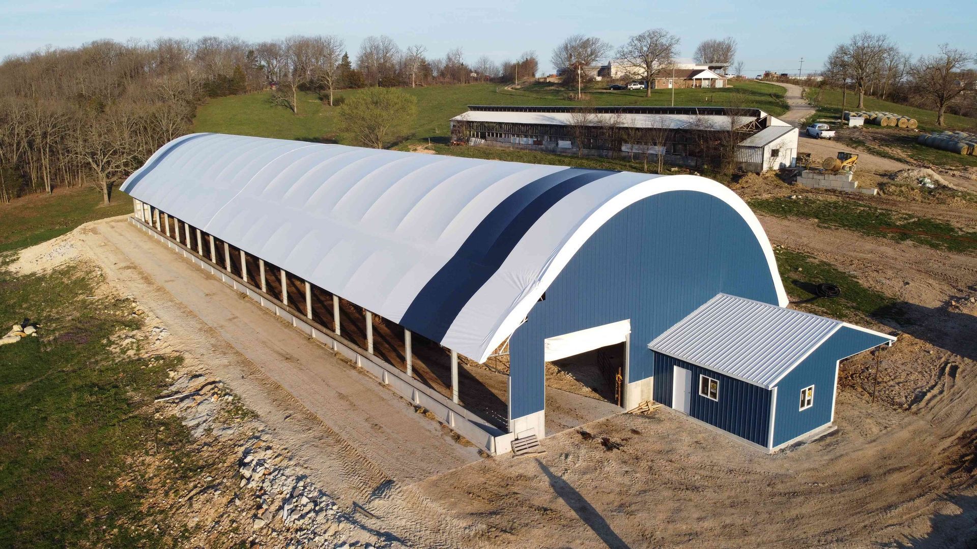 Large blue and white arched building on a construction site.