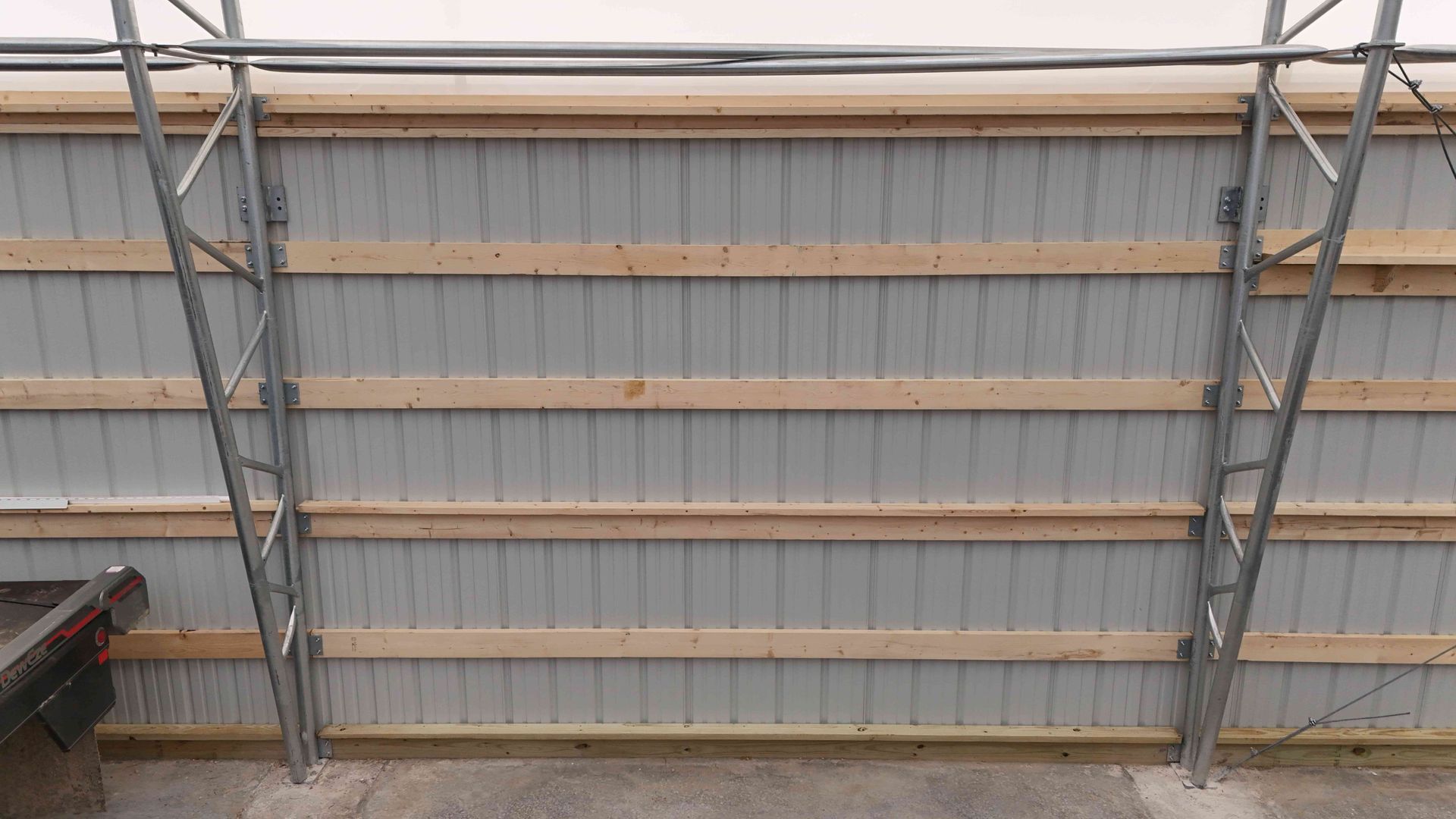 Metal building interior with silver corrugated metal, wooden beams, and metal supports.