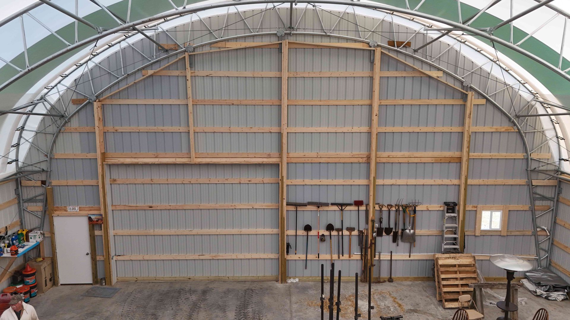 Interior view of a large metal and wood workshop with tools hung on the wall.