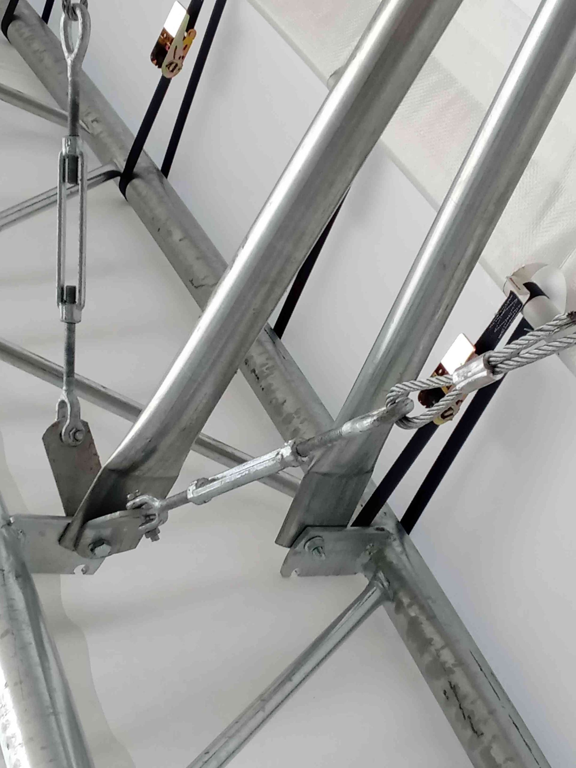Metal tent frame with turnbuckles and cables, likely for structural support.