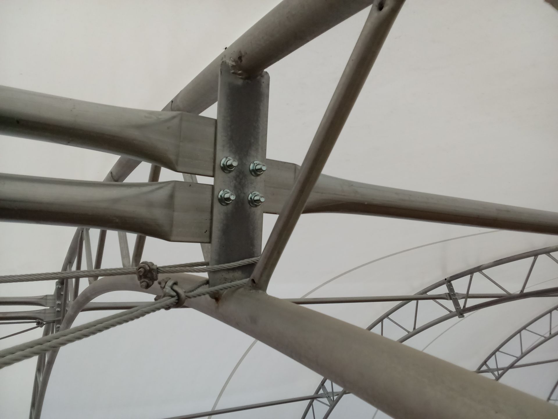 Metal beams joined with bolts, forming a structural connection in a building with a white interior.