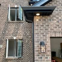 Brick building exterior with windows and a black awning. 