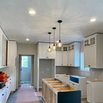 Kitchen with white cabinets, wood island, and three hanging lights.